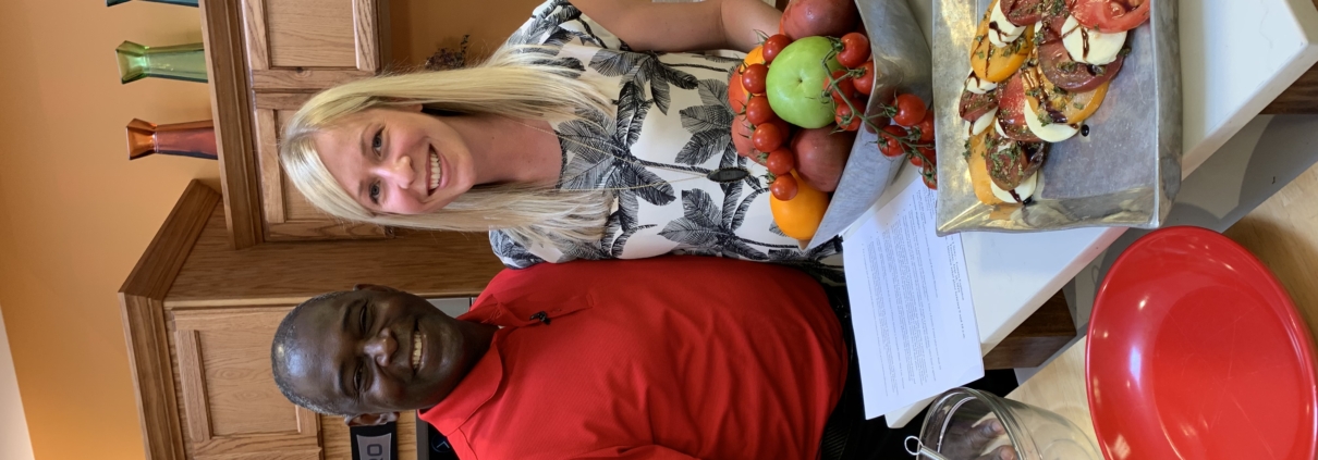 A man and woman standing in front of food.