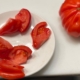 A white plate topped with sliced tomatoes next to a tomato.